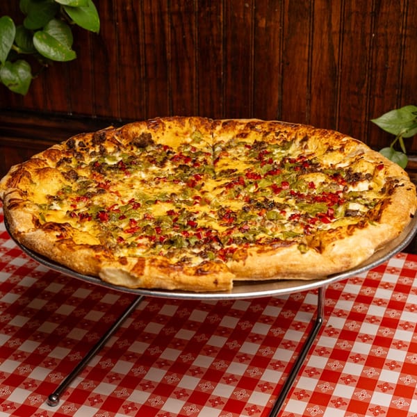 Mattenga's Pizzeria's large pizza with green and red peppers, and meat, on a checkered tablecloth.