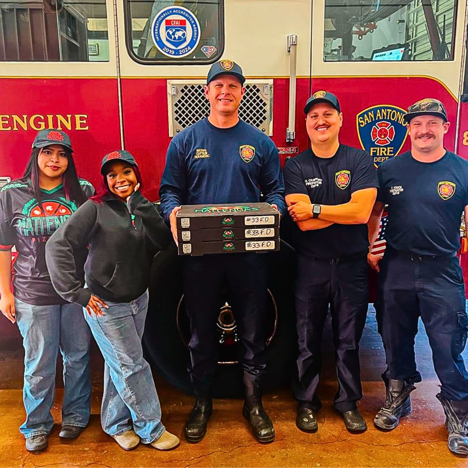Mattenga's Pizzeria staff delivering pizza boxes to San Antonio firefighters in front of a fire truck.