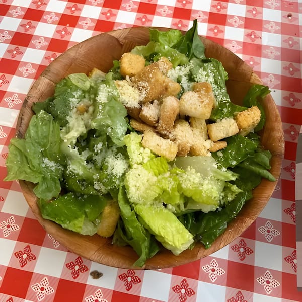 Mattenga's Pizzeria Caesar salad with romaine lettuce, croutons, and Parmesan cheese in a wooden bowl.