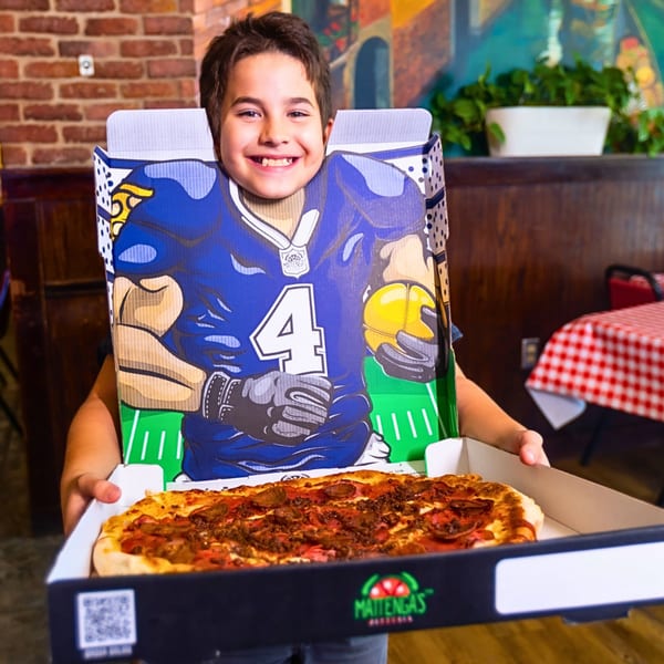 Smiling boy in a football player cutout pizza box, holding a Mattenga's Pizzeria pizza.